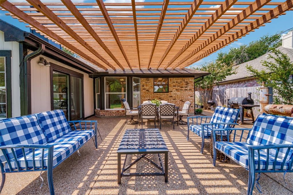 Expansive patio featuring an open-slat pergola, exposed aggregate concrete flooring, and direct access to interior spaces through sliding glass doors