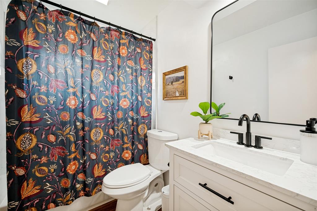 Full Bath with Tub/Shower combination, White Vanity and decorative countertop and integrated sink, matte black faucet, and a large black-framed mirror