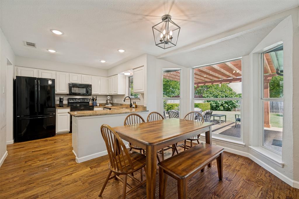 Eat-in kitchen showcases the wood flooring, white cabinetry, and granite countertops