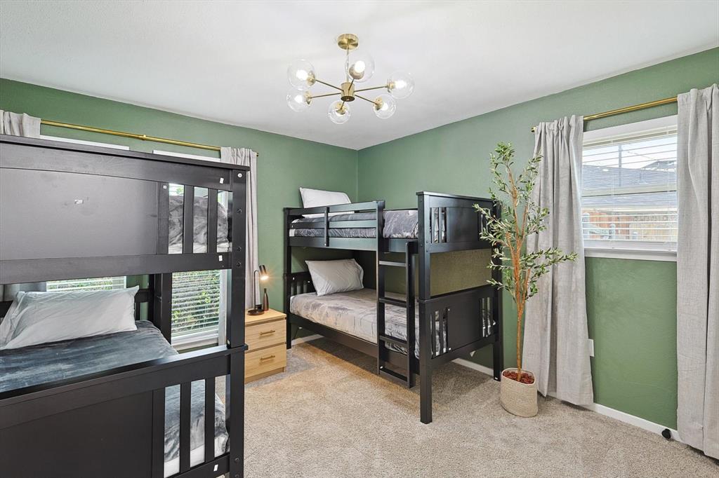 Spacious room featuring two dark-finish bunk beds, light green wall paint, and carpet flooring