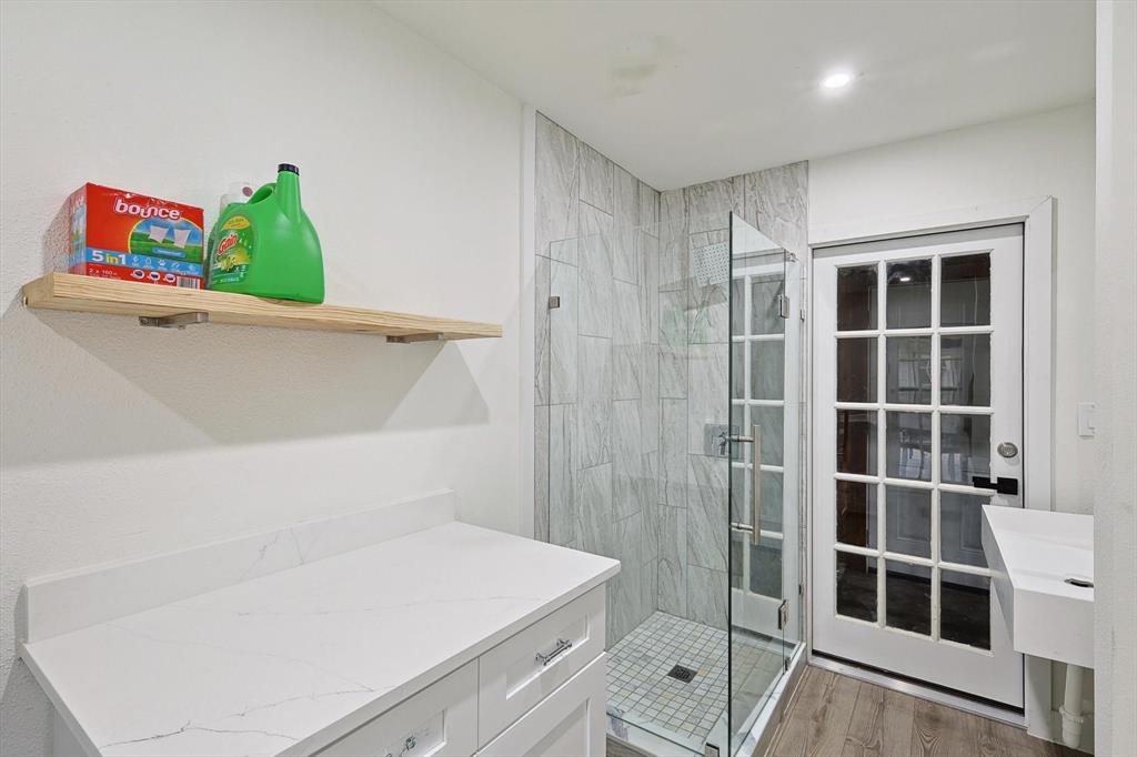 Laundry area featuring a built-in white vanity with a white countertop, a floating wood-finish shelf, and wood-finish flooring