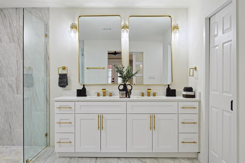 Dual vanity with white cabinetry and gold-tone hardware, featuring a white countertop and gold-tone faucets