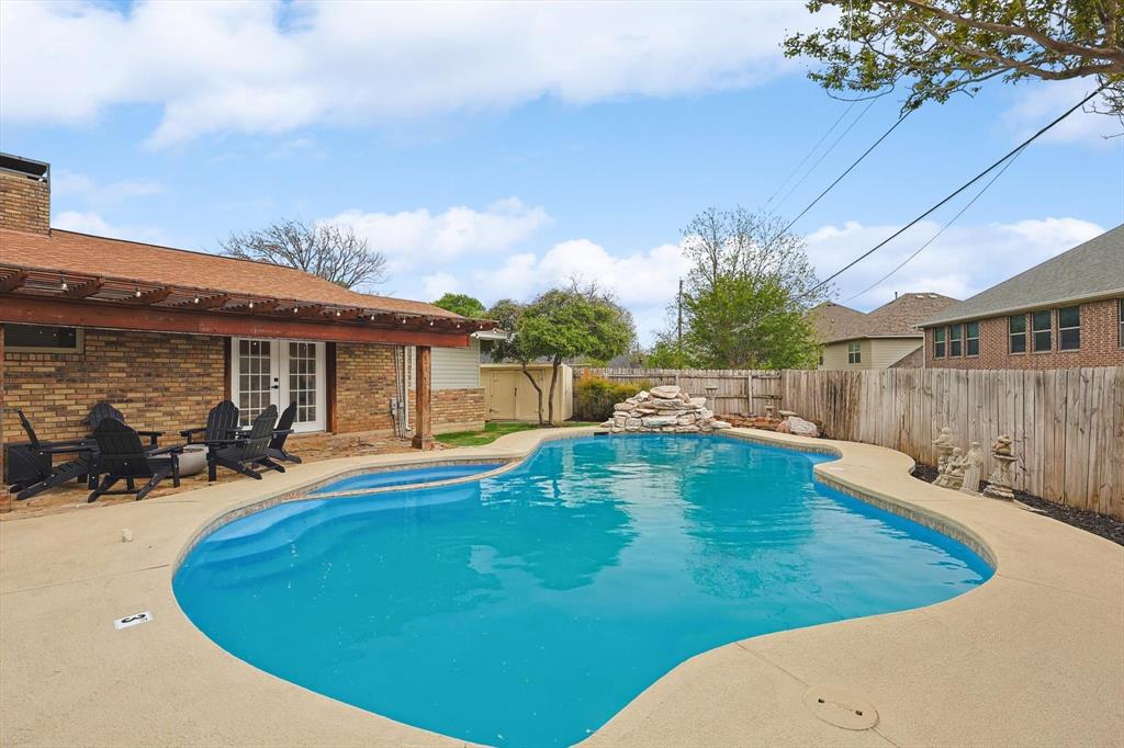 Freeform swimming pool with integrated spa and rock waterfall feature