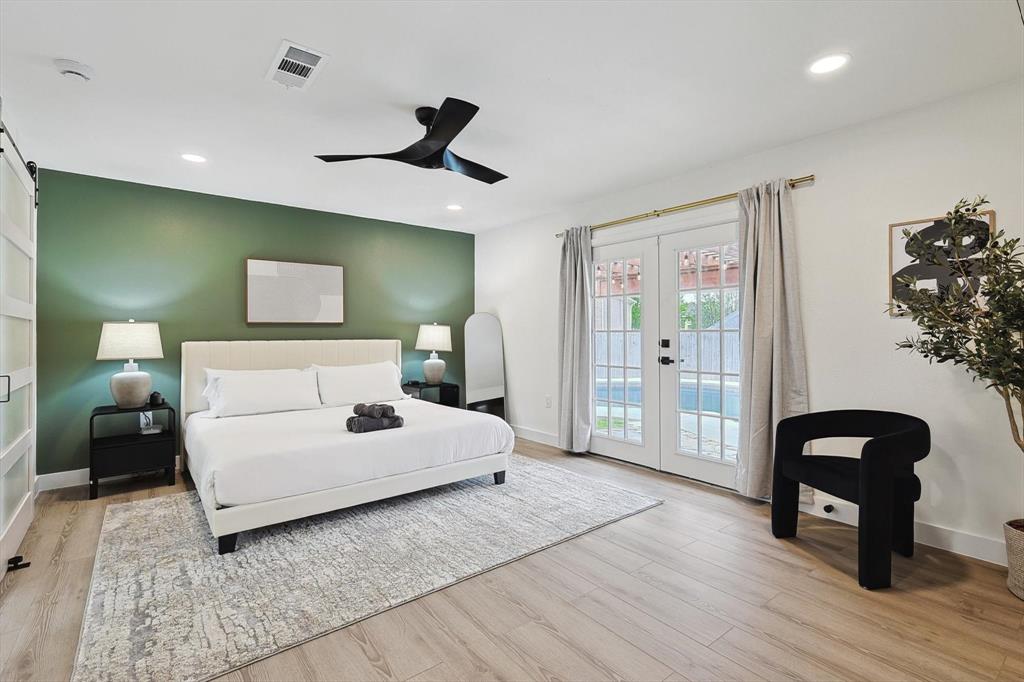 Floor-to-ceiling French doors provide access to the exterior, complemented by light wood-finish flooring throughout