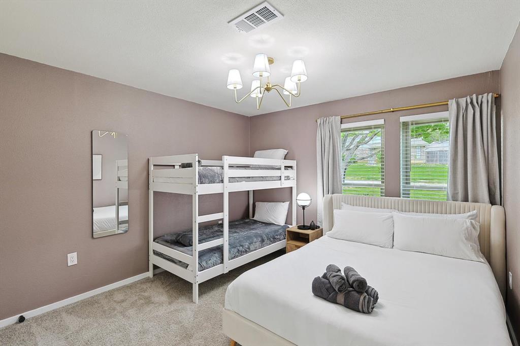 Carpeted bedroom featuring a double bunk bed and a separate bed with a winged headboard