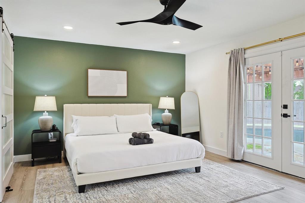 Bedroom featuring a distinctive green accent wall and wood-finish flooring