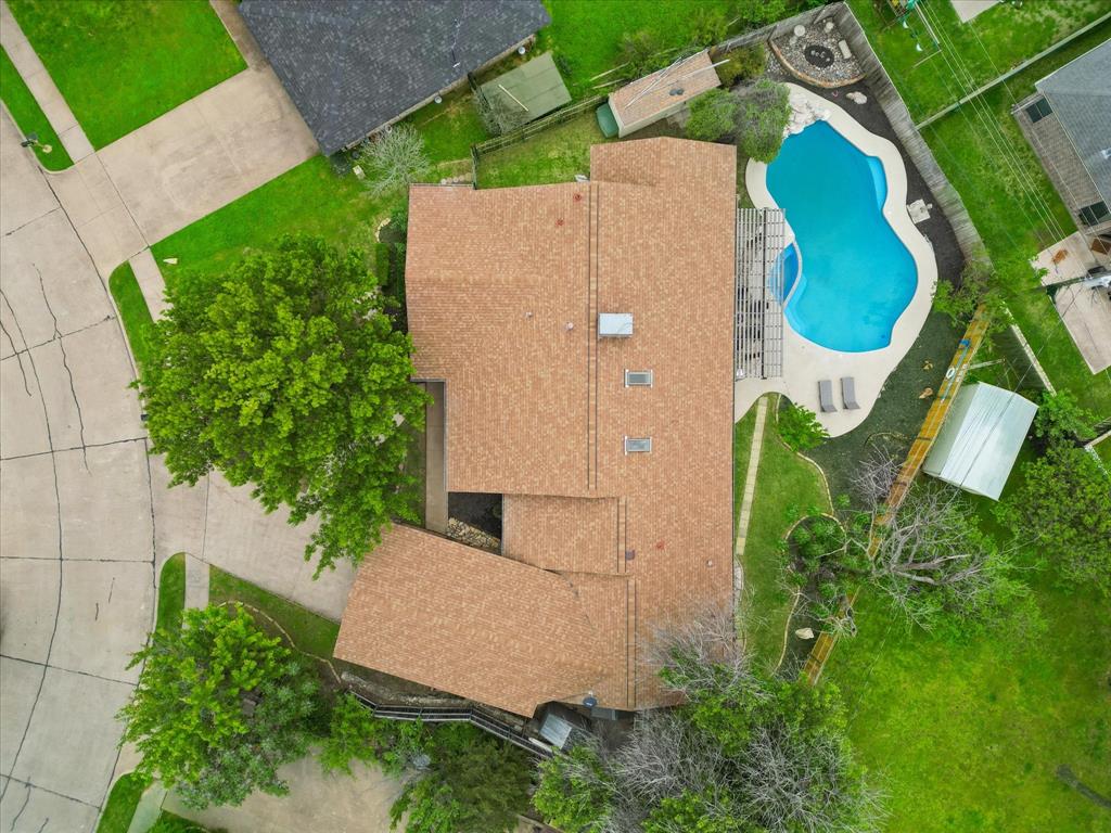 Expansive backyard featuring a freeform swimming pool, concrete patio, and a pergola structure