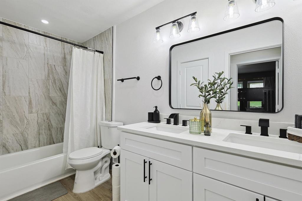 Bathroom featuring a dual-sink vanity with white cabinetry and quartz countertops