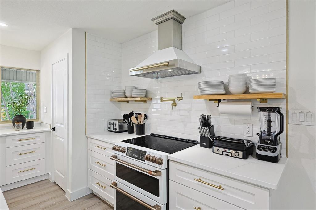 Modern kitchen featuring a stainless steel range hood, white subway tile backsplash, and light wood-finish flooring Modern kitchen featuring a stainless steel range hood, white subway tile backsplash, and light wood-finish flooring