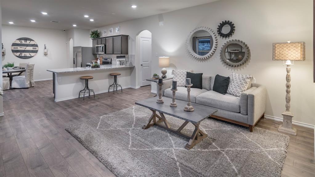 Open-concept living space featuring wood-finish flooring, recessed lighting, a kitchen island with seating, a built-in microwave, and arched doorways