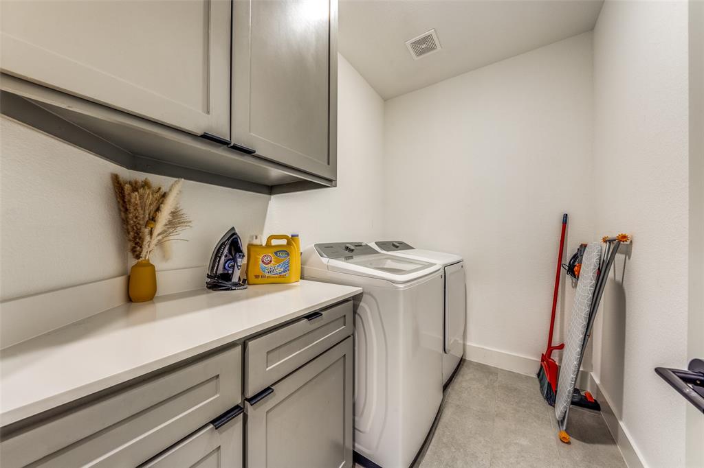 Dedicated laundry area featuring a light countertop, gray cabinetry with black hardware, and tile flooring