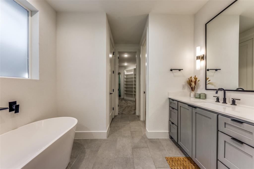 Contemporary bathroom featuring a freestanding tub, a vanity with gray cabinetry and matte black hardware, and a large framed mirror