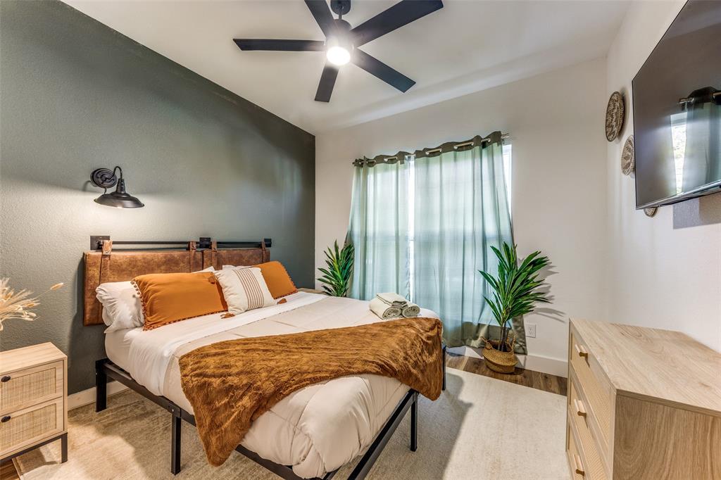 Bedroom featuring a ceiling fan with integrated lighting, a window with light-filtering curtains, and wood-finish flooring