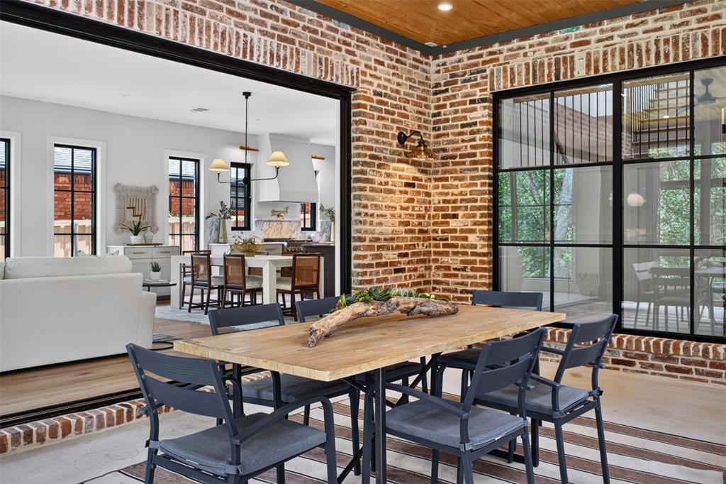 Outdoor dining space featuring exposed brick walls and a wood plank ceiling