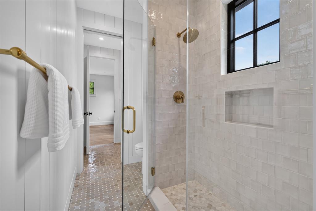 Spacious walk-in shower with clear glass enclosure and brass hardware