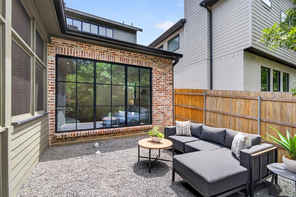 Private outdoor patio featuring a gravel surface, a brick facade, and a large black-framed picture window