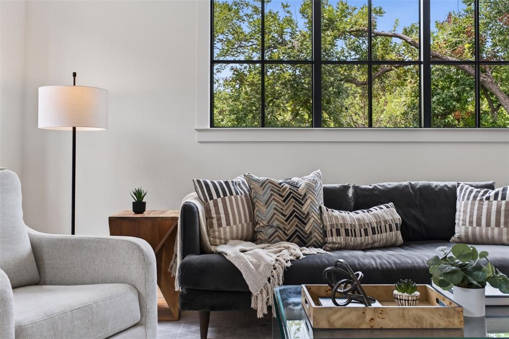 Spacious living area featuring a large picture window with black grid panes, white trim, and abundant natural light