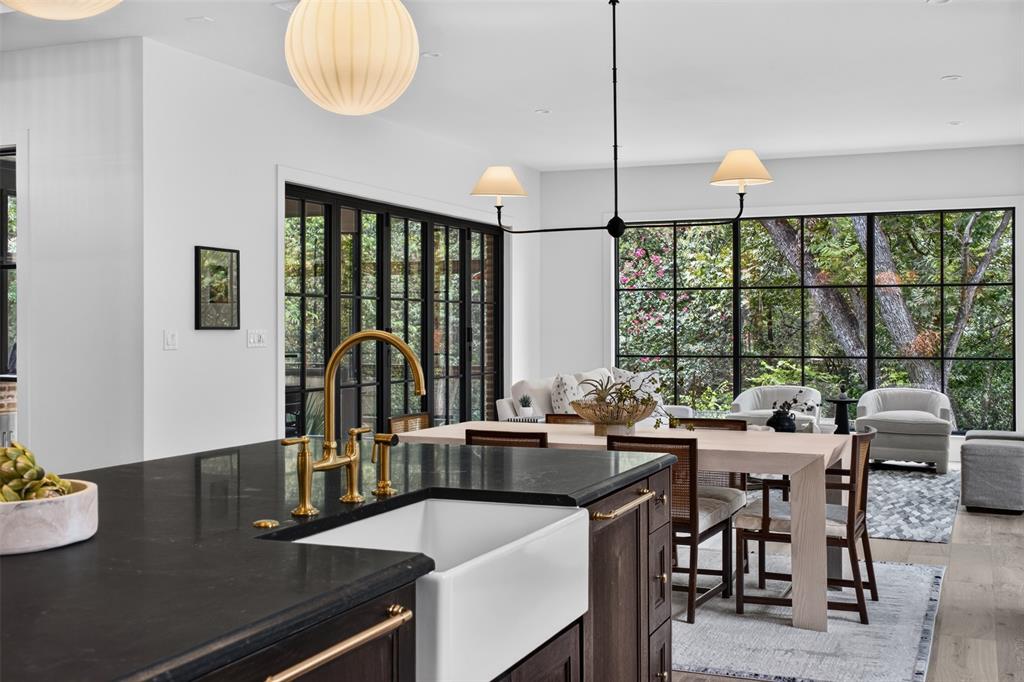 Gourmet kitchen island with a farmhouse sink, brass faucet, and dark countertops