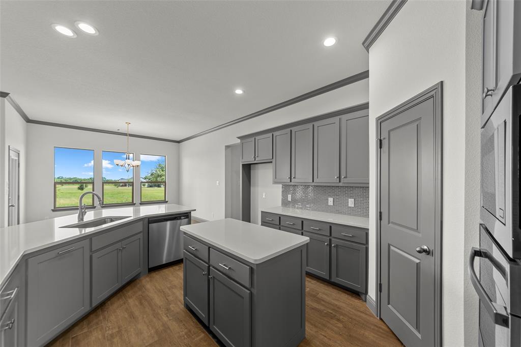 Modern kitchen featuring grey cabinetry, white countertops, stainless steel appliances, and wood-finish flooring