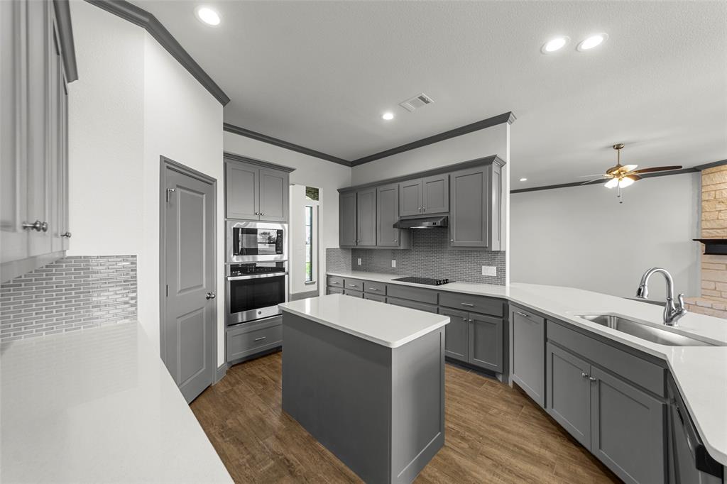 Kitchen featuring an island with a white countertop, gray cabinetry, stainless steel appliances, wood-finish flooring, and recessed lighting