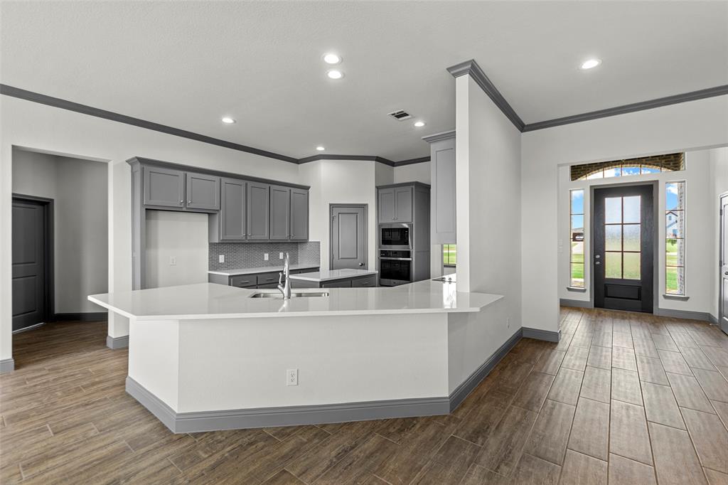 Kitchen featuring gray cabinetry, white countertops, built-in double ovens, and a tile backsplash