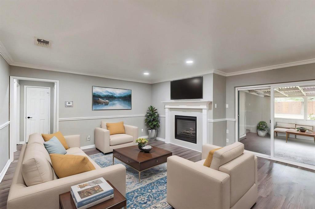 *Virtually staged* Living area featuring wood finished floors, crown molding, a glass covered fireplace, recessed lighting, and baseboards