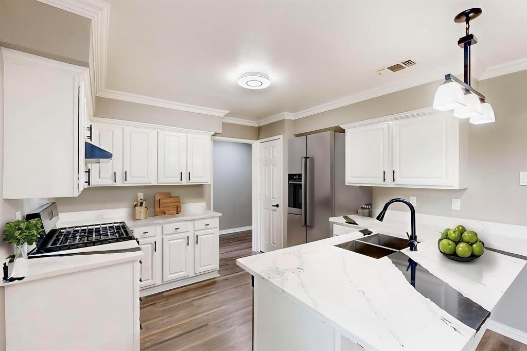 *Virtually staged*  Kitchen featuring a sink, light wood-style floors, white cabinetry, and crown molding