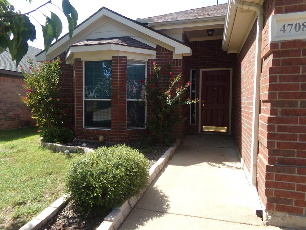 Brick facade residence featuring a covered entry, a paneled front door with sidelight, and a bay window with blinds