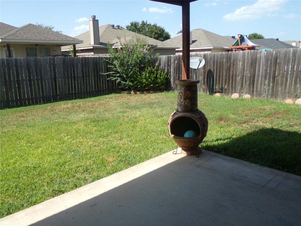 Expansive backyard featuring a lush lawn, privacy fencing, and a concrete patio pad