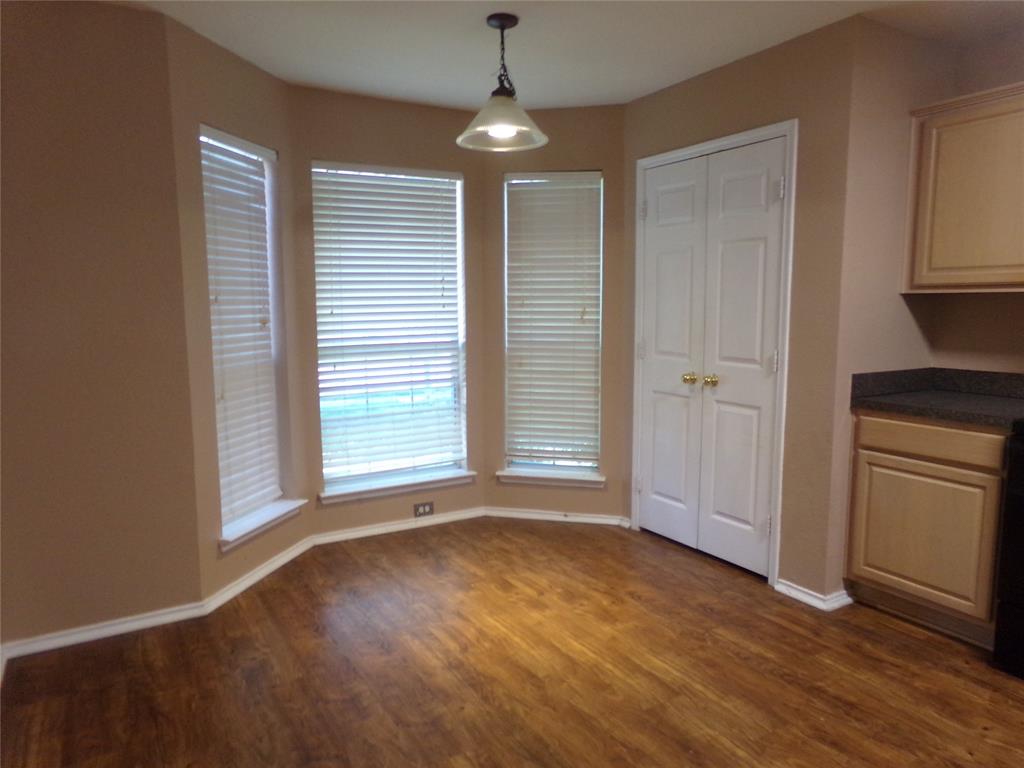 Bay window dining area featuring wood-finish flooring, a ceiling-mounted light fixture, white blinds, and base molding