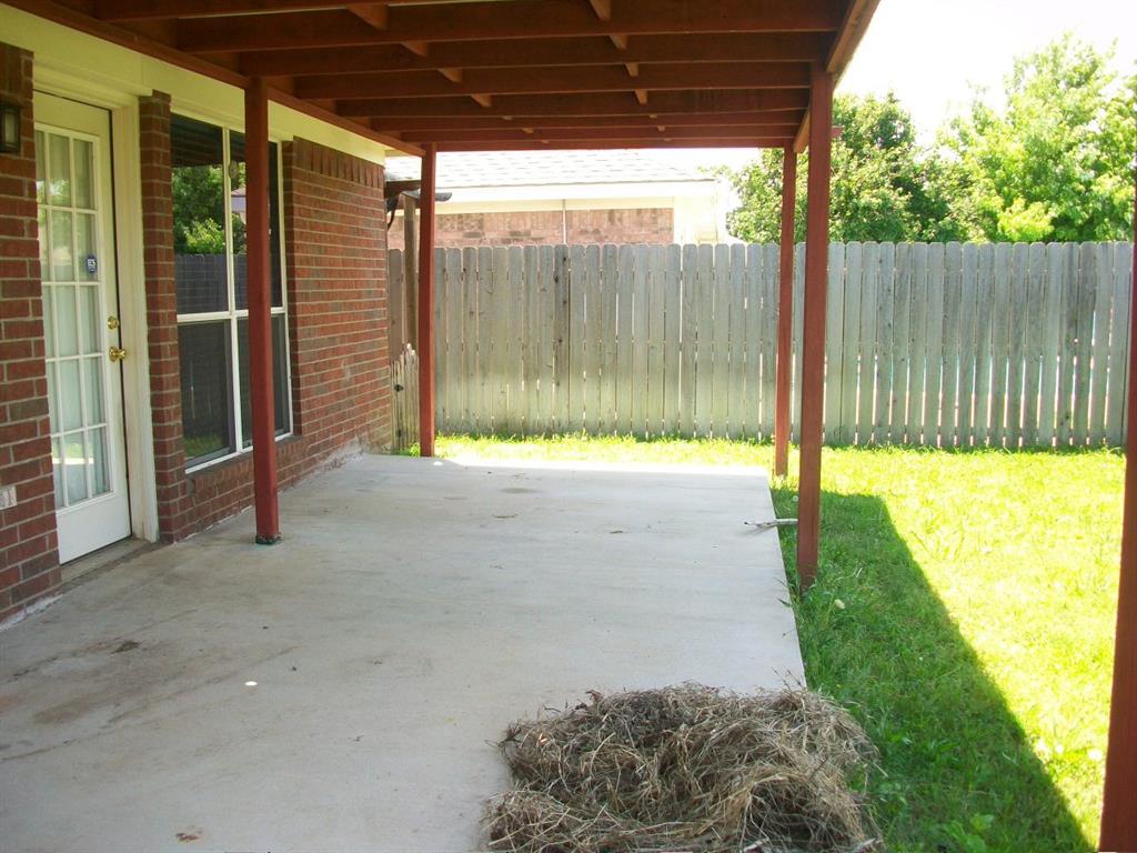 Covered concrete patio with wooden support beams and an exposed rafter ceiling