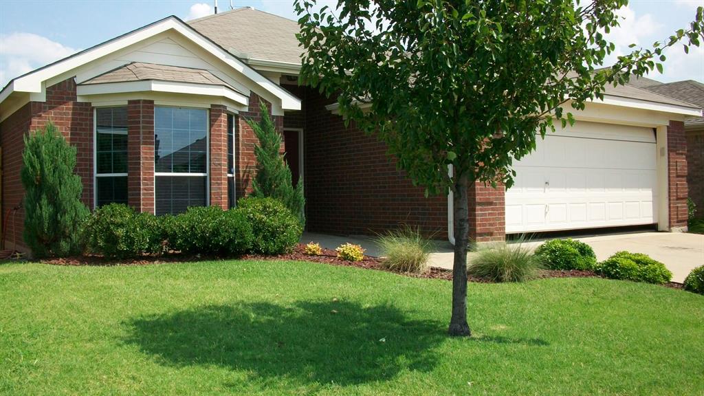 Brick exterior featuring a bay window, attached garage with white door, and a verdant lawn with mature landscaping Brick exterior featuring a bay window, attached garage with white door, and a verdant lawn with mature landscaping