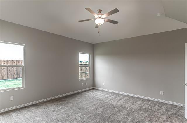 Spacious room featuring vaulted ceilings, a ceiling fan with integrated lighting, two windows, and textured gray carpeting