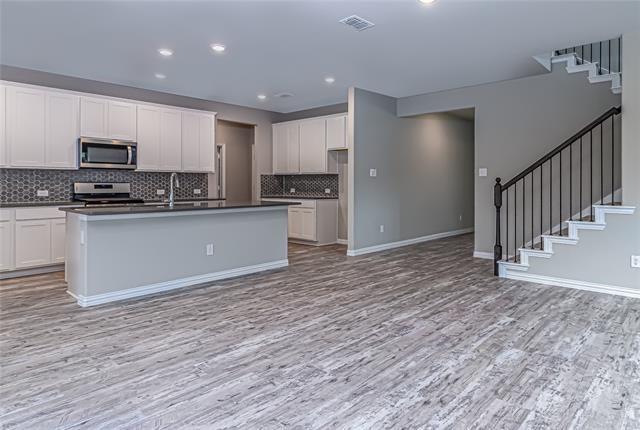 Open-concept living space with wood-finish flooring extending into the kitchen