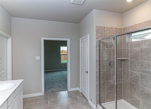 Shower enclosure featuring clear glass panels, a chrome-finish shower head, and an integrated corner shelf
