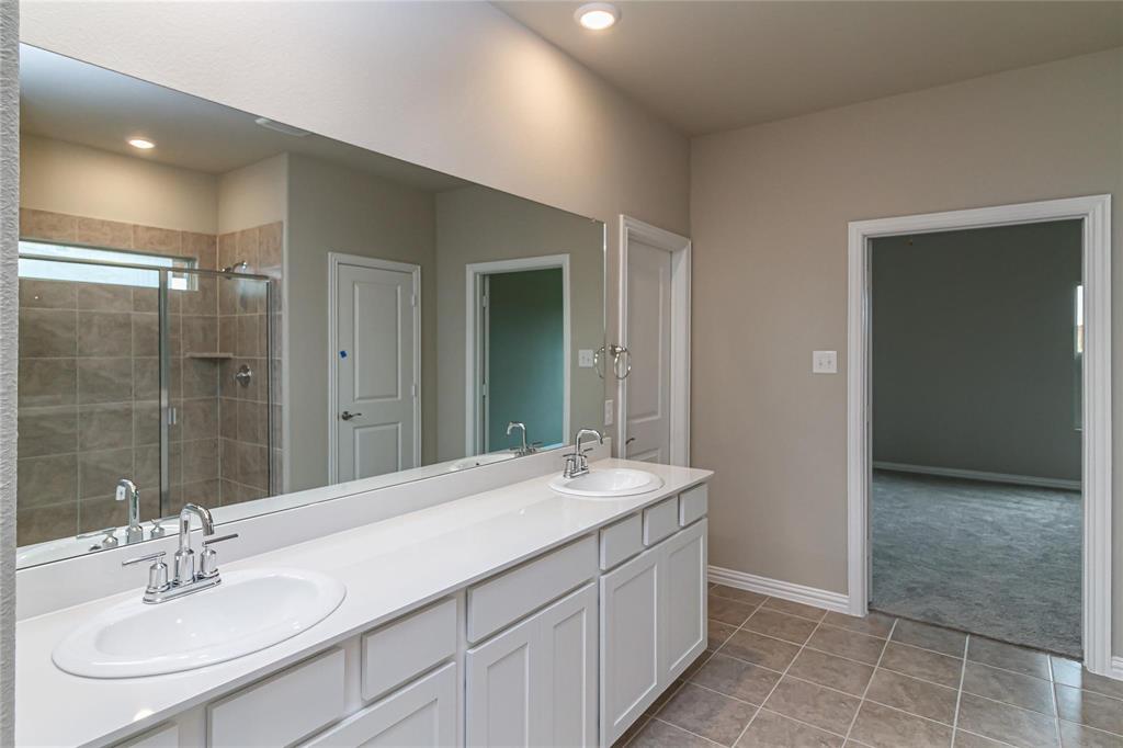 Dual vanity with white cabinetry, integrated sinks, chrome faucets, and an expansive wall-mounted mirror