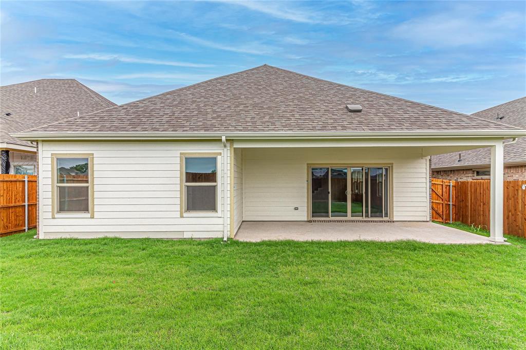 Rear exterior featuring a covered patio with concrete flooring, a sliding glass door, and white siding