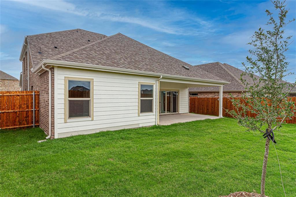 Expansive backyard featuring a covered patio, manicured lawn, and privacy fencing