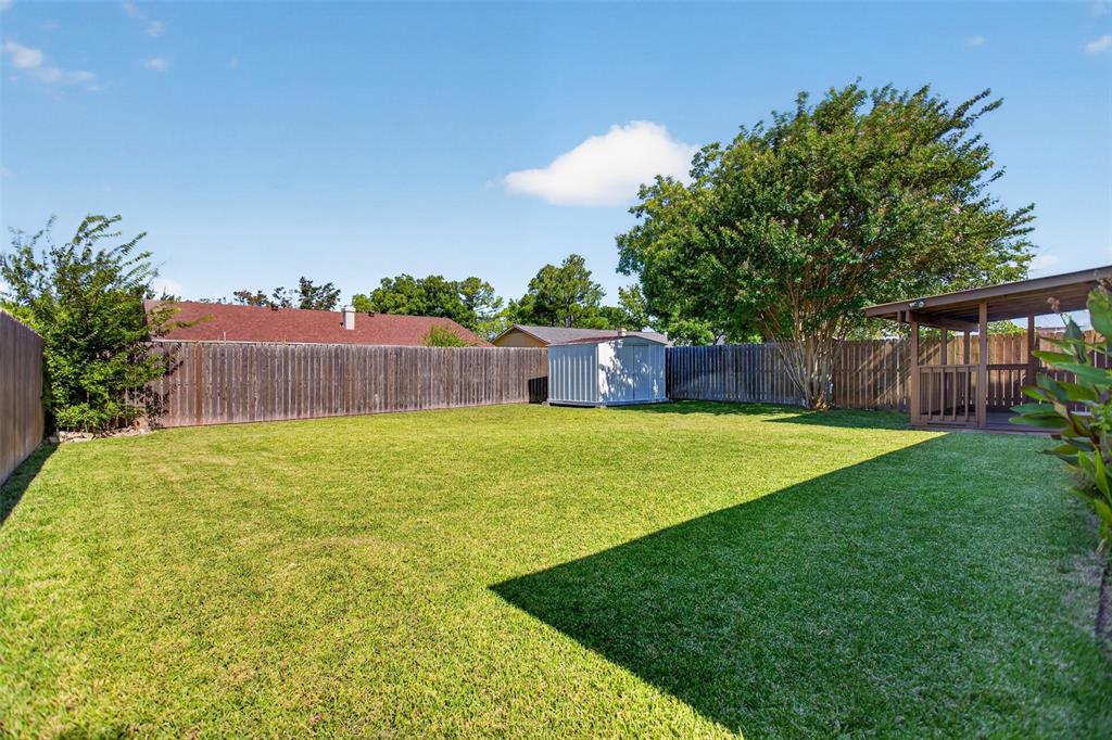 Large backyard grass area with storage shed.