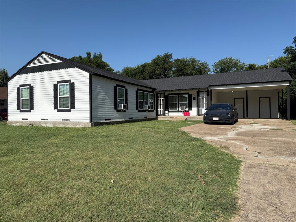 Exterior featuring white horizontal siding with dark trim, a dark shingle roof, and a covered carport