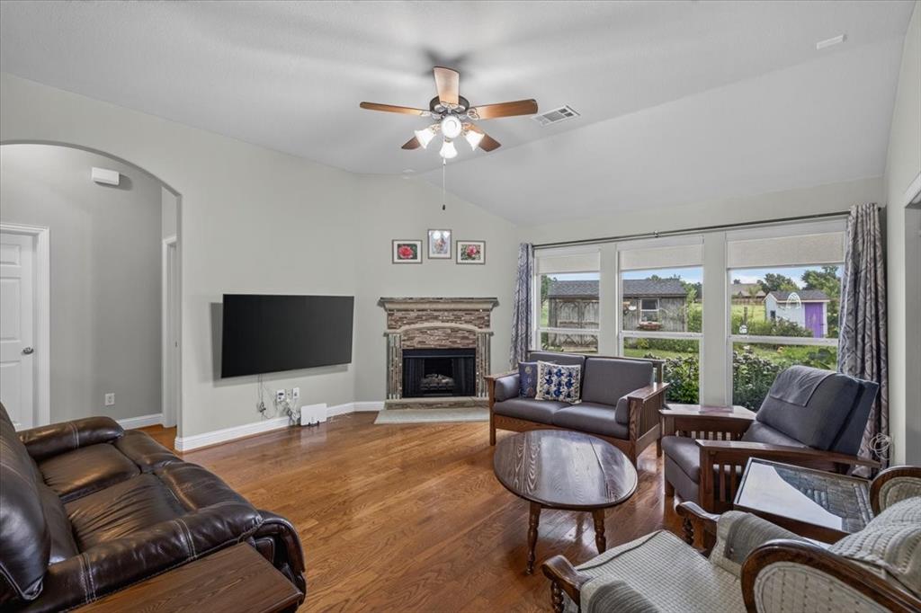 Living room with wood flooring, a fireplace and lots of windows for natural light.