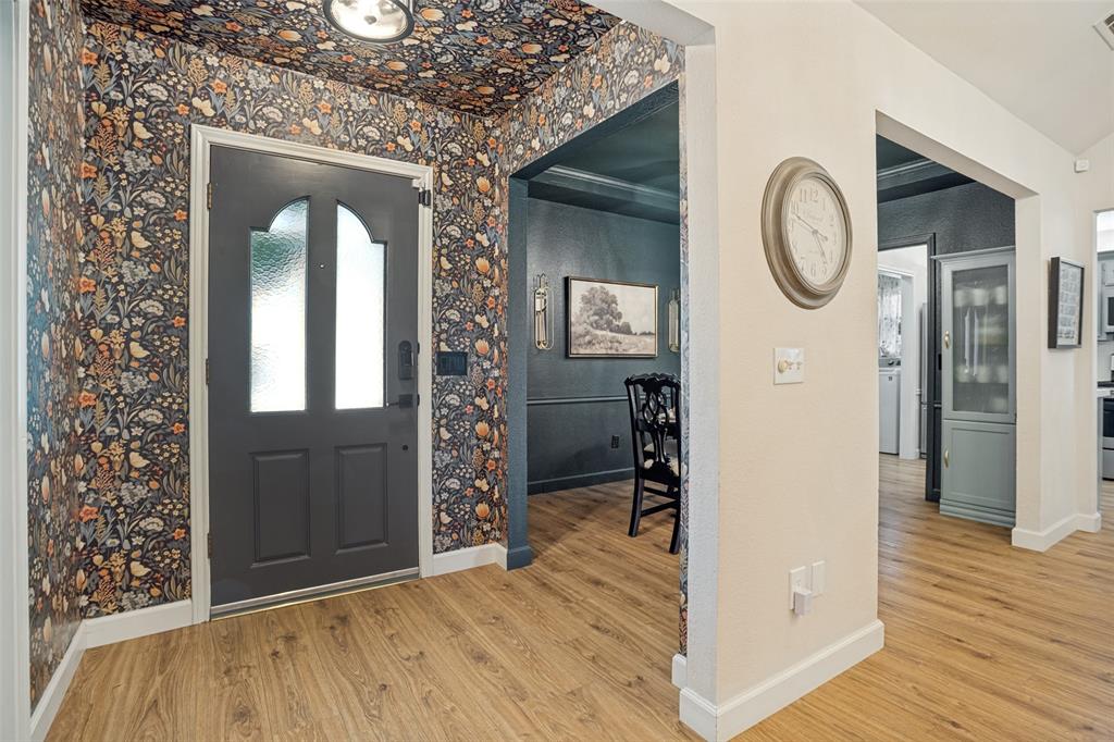 Entryway with patterned wallpaper, wood-finish flooring, and a contemporary ceiling light fixture