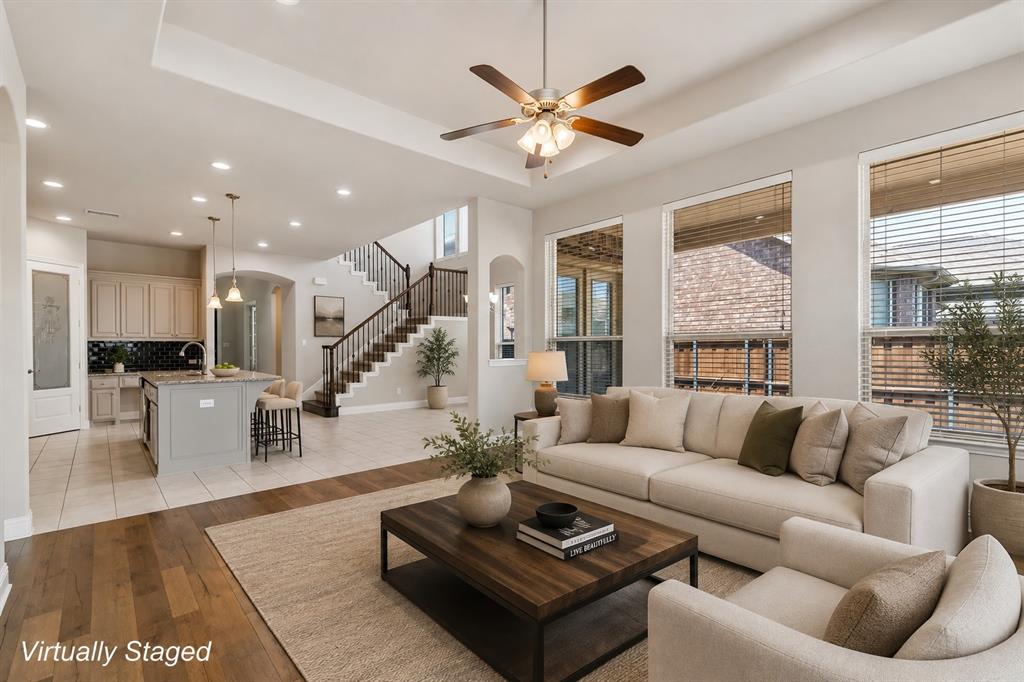 Open-concept living area featuring a cream upholstered sofa, wood-finish flooring, and a dark wood coffee table