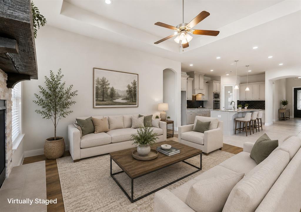 Open-concept living area featuring a tray ceiling, recessed lighting, and wood-finish flooring