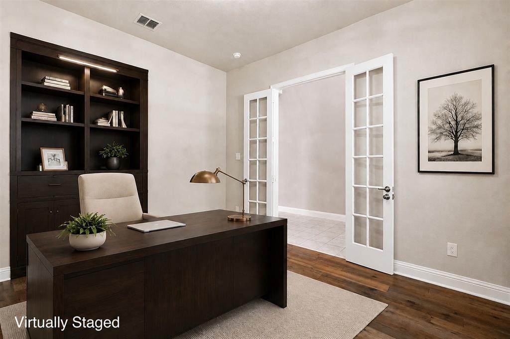 Built-in dark wood cabinetry with integrated lighting, wood-finish flooring, and double French doors with glass panes