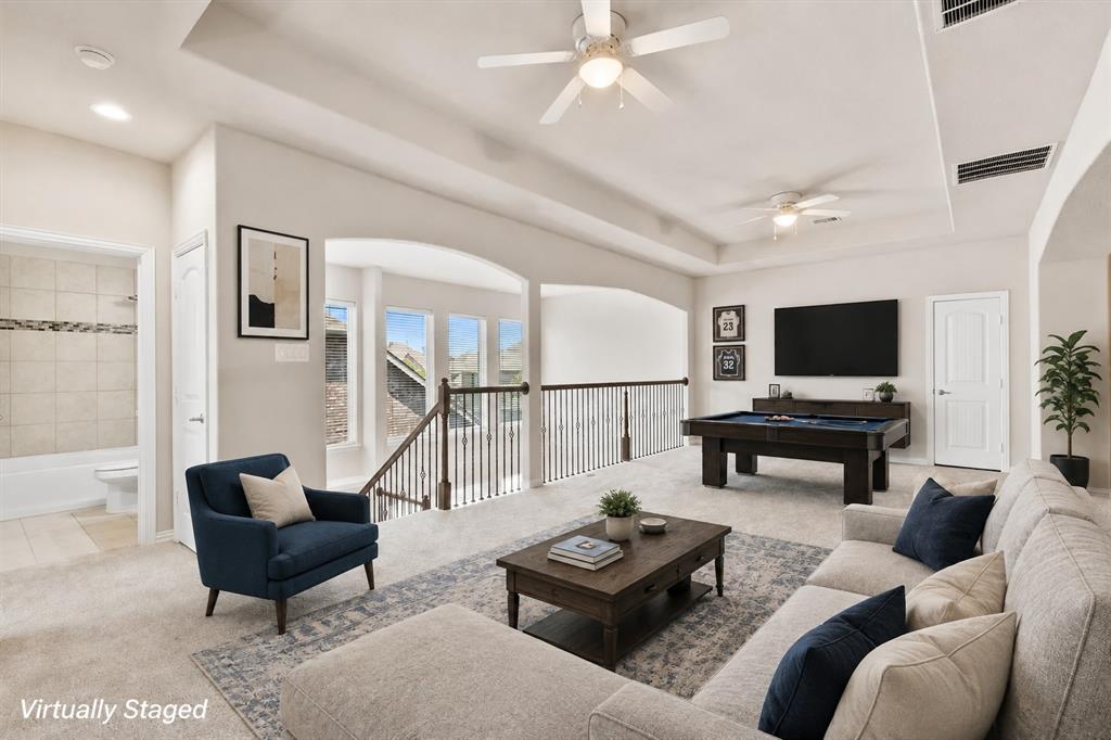 Carpeted open area with ceiling fans, a tray ceiling, and a built-in wall unit