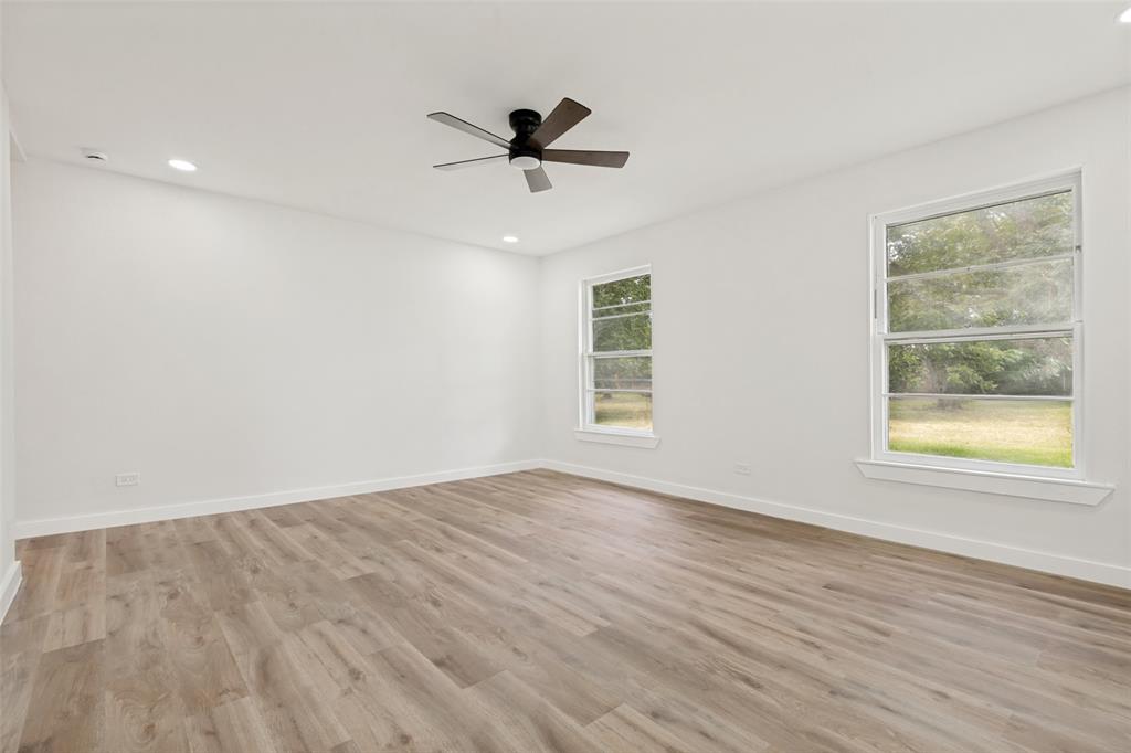 Spacious interior featuring wood-finish flooring, two large windows, a ceiling fan, recessed lighting, and white baseboards