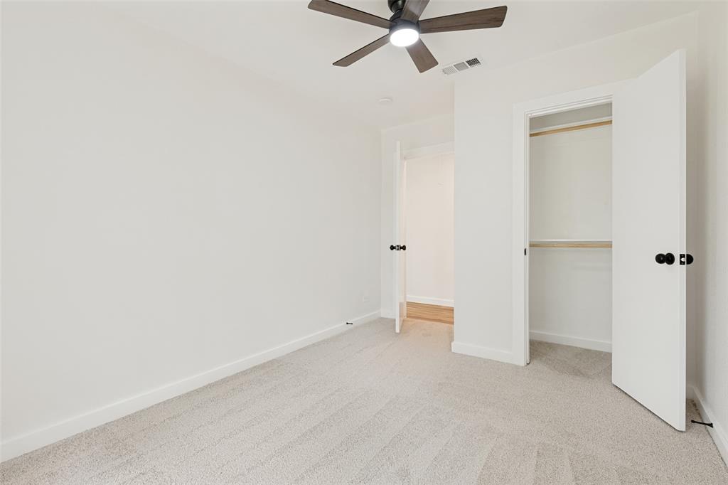 Carpeted room featuring a ceiling fan with integrated lighting, white walls, and a closet with bi-fold doors