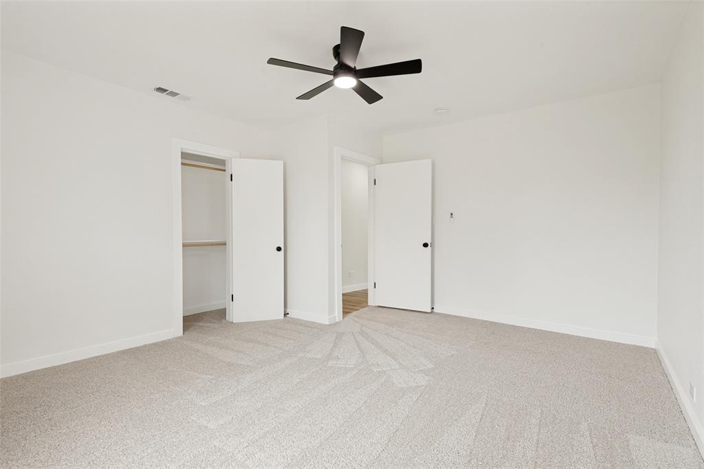 Neutral-toned carpeted room featuring a ceiling fan with black blades, white walls, and white trim