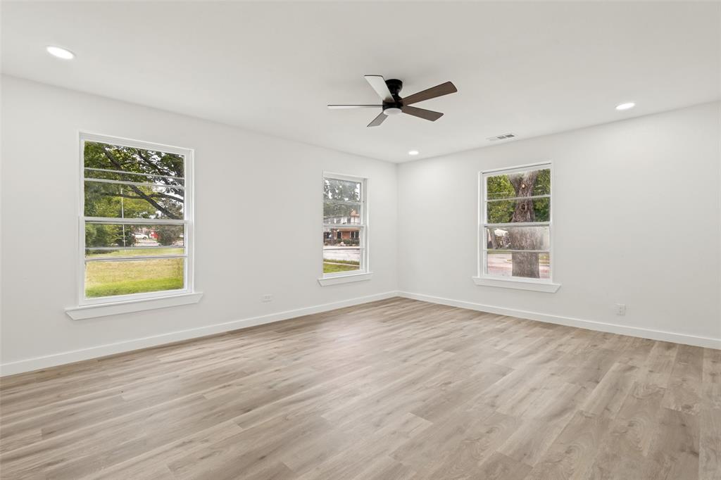 Spacious room featuring light wood-finish flooring, recessed lighting, and a contemporary ceiling fan Spacious room featuring light wood-finish flooring, recessed lighting, and a contemporary ceiling fan